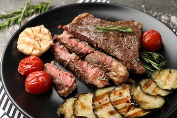 Delicious grilled beef steak with vegetables and spices on table, closeup