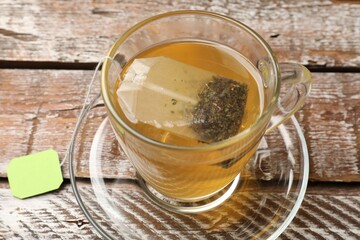Tea bag in glass cup on wooden table, above view