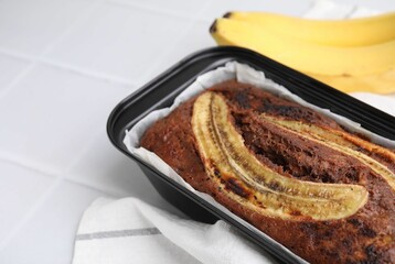 Delicious banana bread and fresh fruits on white tiled table, closeup