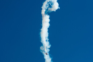 Pilot showing off in the sky with a turbo-propeller or single-engine plane, leaving a trail of...