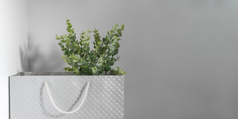 Houseplant in shopping bag on grey background. Sale banner for plant shop. Selective focus, copy space
