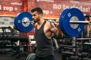 concentrated man athlete doing squats in a gym. front view