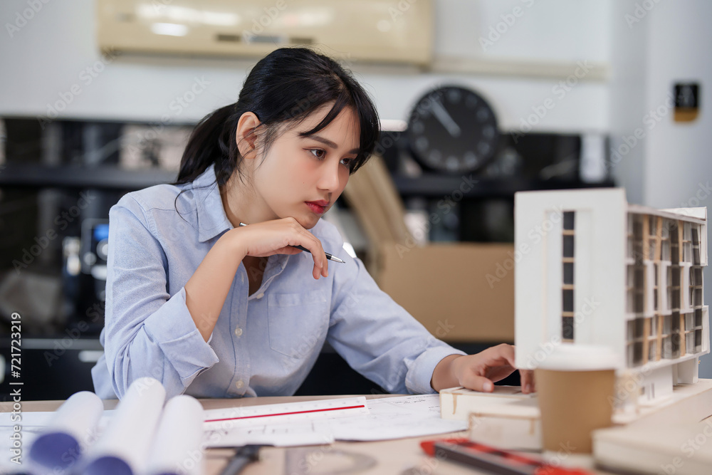 Poster asian architect engineer women inspecting design of architecture building model and writing notes in