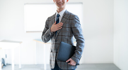 オフィスで胸に手を当てるジャケットを着た若い男性