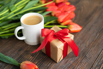 Fresh orange tulips and cappuccino mug with spring composition. Greeting card with copy space for Valentine's Day, Woman's Day and Mother's Day.