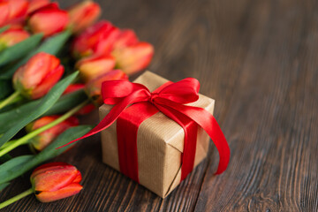 Bouquet of beautiful fresh orange tulips with gift boxe and red paper hearts on wood background....