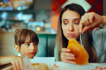 Mom Finding a Nasty Ingredient in a Fast Food Sandwich. Mom removing salad from a burger for a picky eating child
