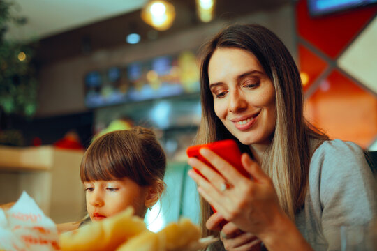 Mother Checking her Phone at the Table in a Restaurant . Mom scanning a qr code in a diner making payment online

