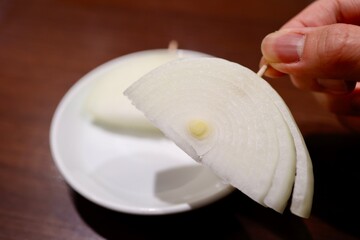 爪楊枝に刺さった半月切りした生玉ねぎ