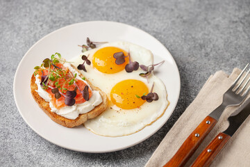 Eggs with microgreens and sandwich with cheese and salmon. Healthy breakfast