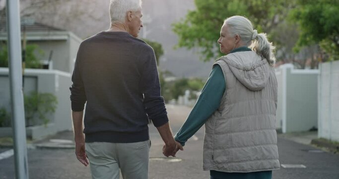Old couple on walk in neighborhood together holding hands with hug, smile or love from back. Relax on retirement holiday, senior man and happy woman embrace in street for calm, healthy outdoor stroll