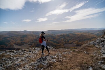 Fototapeta premium woman on mountain peak looking in beautiful mountain valley in autumn. Landscape with sporty young woman, blu sky in fall. Hiking. Nature