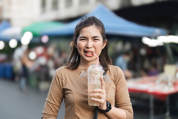 Happy young Asian Traveler foodie woman enjoy drinking longan juice at outdoor night market street...