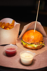 cheeseburger with chicken and fries with sause on the board. High quality photo.Dark photo