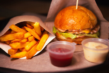 Side view of cheeseburger with chicken and fries with sauce. High quality photo. Selective focus. Horizontal Dark photo