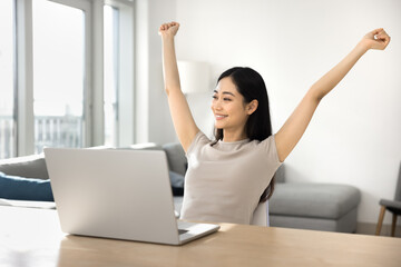 Cheerful Chinese freelancer girl celebrating business project completion, raising hands in...