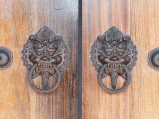 Old Chinese style door handle on wooden door, antique oriental door knocker. Traditional Chinese doors with brass lion head door knockers