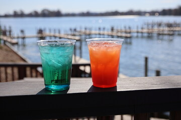 Colorful mixed drinks sitting on the deck of a restaurant near a marina	
