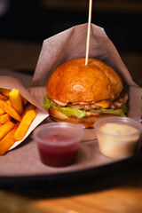 Side view of cheeseburger with chicken and fries with sauce. High quality photo. Selective focus. Unhealthy eating concept