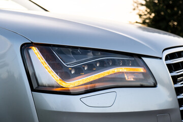Headlight turned on in Clean car after Washing luxury silver car. Sedan car exterior of modern...