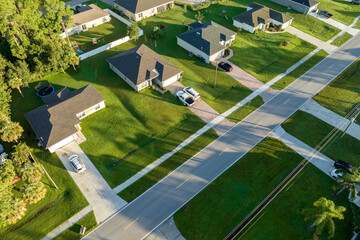 Aerial view of street traffic with driving cars in small town. American suburban landscape with private homes between green palm trees in Florida quiet residential area