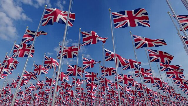 Brithish UK flags blowing in the wind against a Blue Sky. The national flags of the United Kingdom, representing the union of England, Scotland, Wales, and Northern Ireland. European country flags.