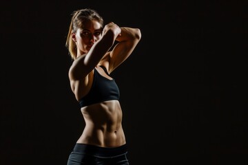 Fototapeta na wymiar Woman showcasing fitness and physique on black background