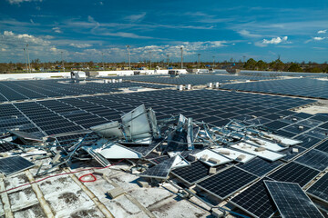 Photovoltaic solar panels destroyed by hurricane strong wind mounted on industrial building roof for producing green ecological electricity. Consequences of natural disaster in Florida © bilanol