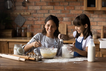 I like cooking with mom. Little latina girl assist mommy mix dough for pancakes on healthy lunch...