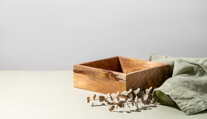 Empty wooden box and dry eucalyptus branches on a light background.