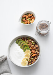 Granola with banana and kiwi on a white table.