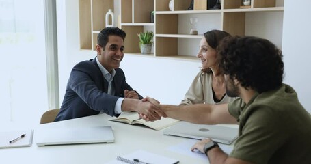 Happy Indian and Middle Eastern businessmen shaking hands over meeting table, getting agreement, ending negotiation with handshake greeting good bye gesture, smiling, thanking for collaboration
