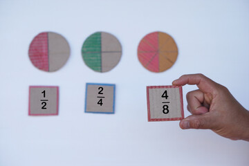 Hand hold paper card with fraction numbers. Circle paper show parts of color separation. Concept,...