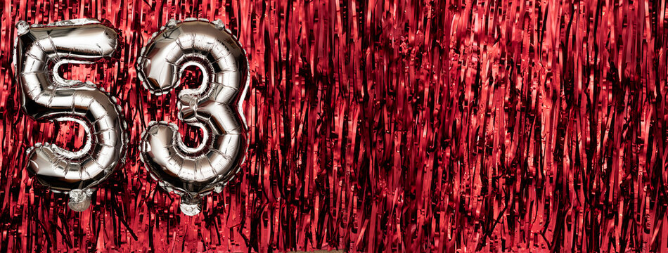 Silver foil balloon number fifty-three. Birthday or anniversary card with the inscription 53. Red tinsel background. Anniversary celebration. Banner.