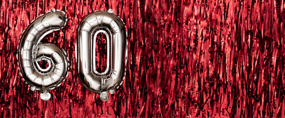 Silver foil balloon number sixty. Birthday or anniversary card with the inscription 60. Red tinsel...