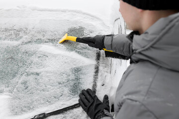 Man cleaning snow from car windshield outdoors, closeup