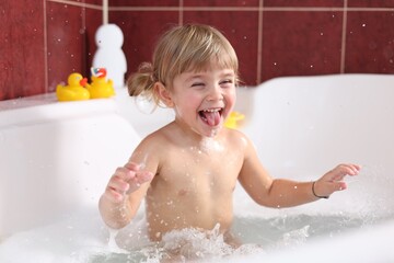 Happy girl having fun in bathtub at home