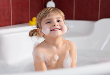 Happy girl bathing in tub at home