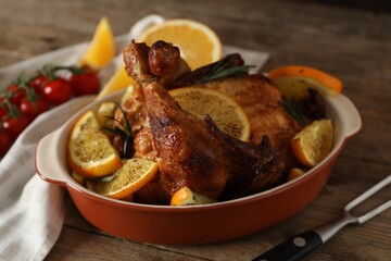 Baked chicken with orange slices on wooden table