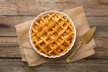 Tasty homemade quince pie and cake server on wooden table, flat lay