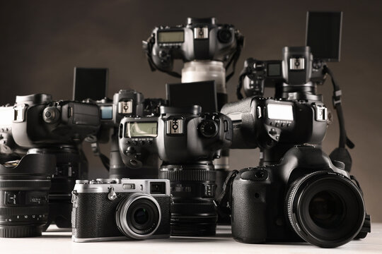 Modern cameras on white table against dark background, closeup