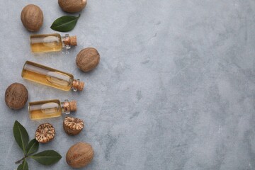Nutmeg essential oil, nuts and leaves on light grey table, flat lay. Space for text