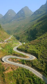Motorcycle riding on scenic winding mountain road on the Ha Giang Loop, Vietnam.
