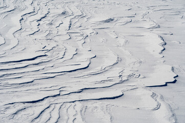 太陽光にくっきりと浮かび上がる雪原の風紋の模様。