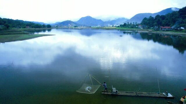 Aerial view of fishermen fishing using traditional bamboo rafts in a beautiful swamp surrounded by mountains in Agam Regency, West Sumatra.