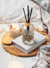 Home fragrance in glass bottle and bamboo sticks with scented candle,  paper book.