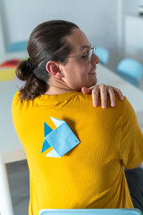 A person unaware of a paper fish prank stuck on their back, a classic April Fools' Day joke
