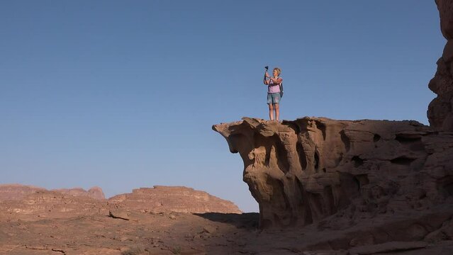 Travel and adventure. Woman tourist on sunset excursion taking pictures of landscapes in the desert. Desert sunrise tour on Wadi rum desert outdoors. Young woman hiker enjoying nature desert view.