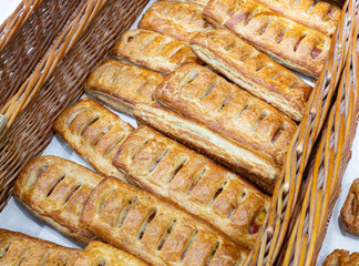 Freshly baked crispy bread buns on a counter or shelf in a store, close-up. Bakery products are sold in the market. Fresh bakery. Assortment of pastries.