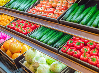 Assortment of fresh vegetables on store shelves, on market counter.